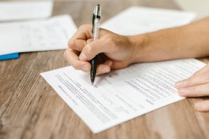 A frustrated worker reviewing their paycheck and calculating lost wages, symbolizing wage theft and the need to file a claim.