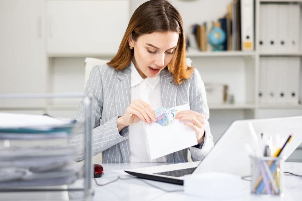 An employee reviewing their paycheck with a concerned expression, highlighting the issue of unpaid overtime and wage violations.